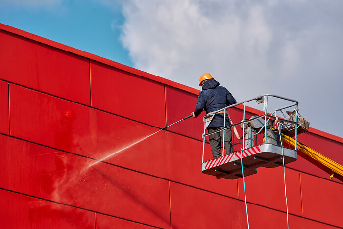 Boom Lift Commercial Cleaning Exterior 
 Worker wearing safety harness washes wall facade at height on modern building in a crane.